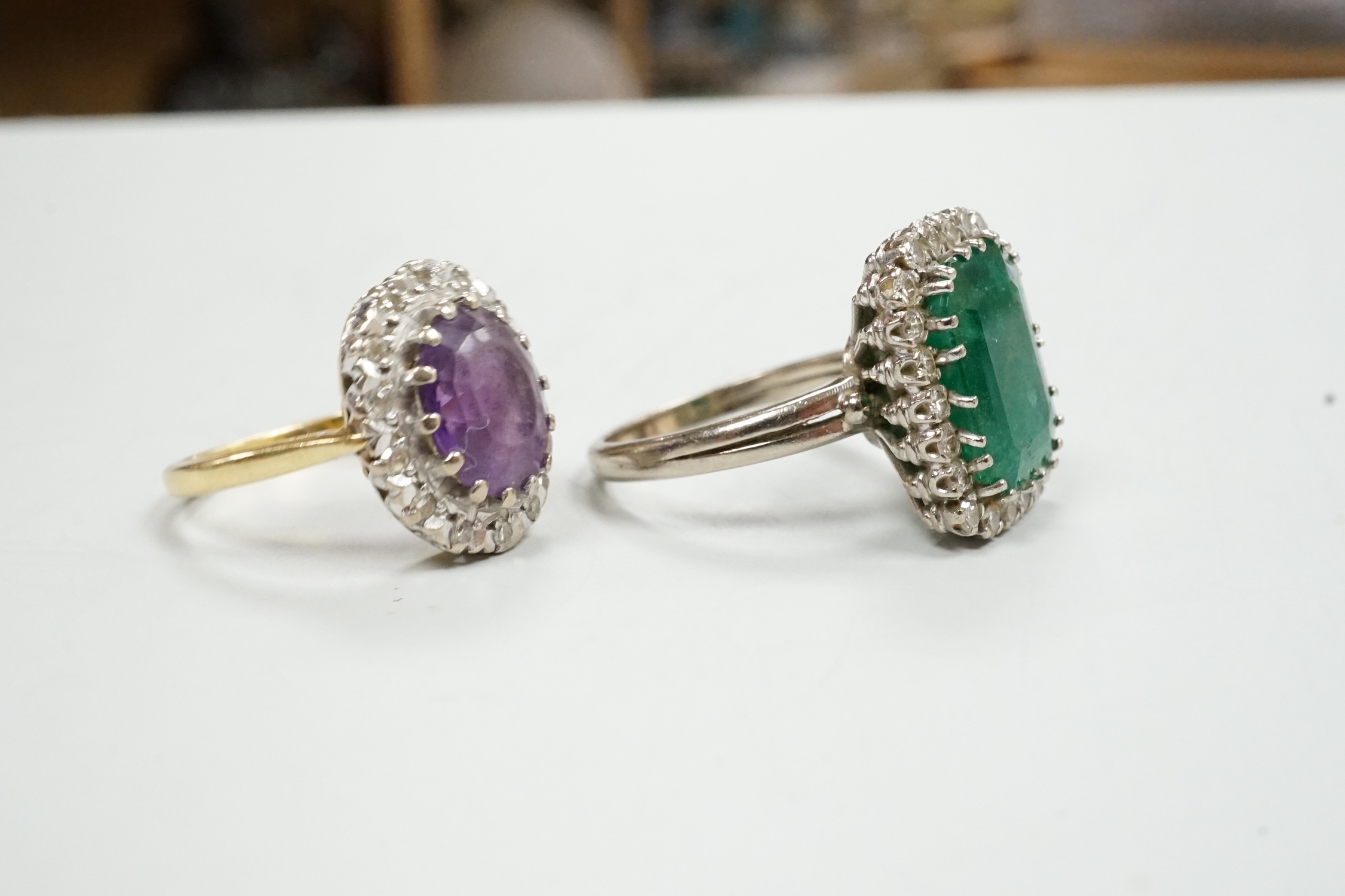 A modern 18ct gold, amethyst and diamond set oval cluster ring, size K/L and a white metal, emerald and diamond cluster set ring, gross weight 11.8 grams.
